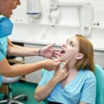 Female dentist examining teeth of woman