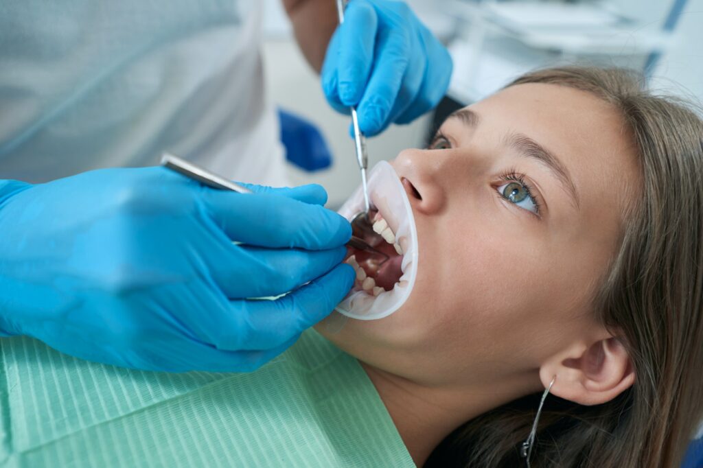 Pedodontist examining teeth and gums of adolescent girl