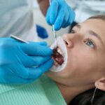 Pedodontist examining teeth and gums of adolescent girl